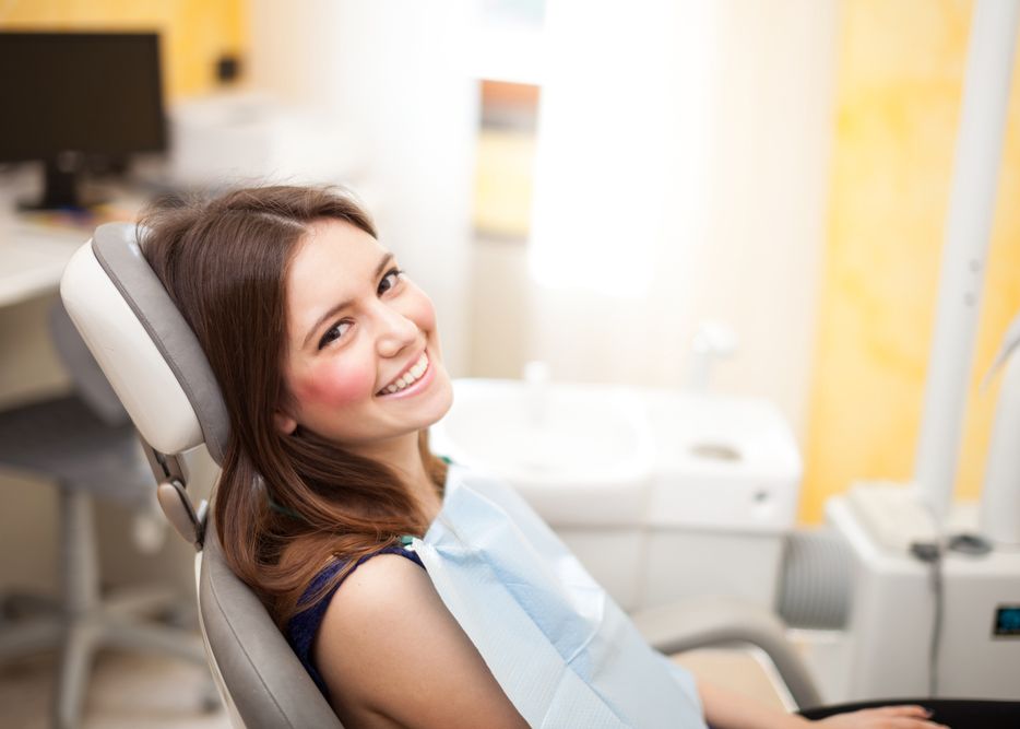 <p>A beautiful, young woman smiling in a dental chair.</p>
