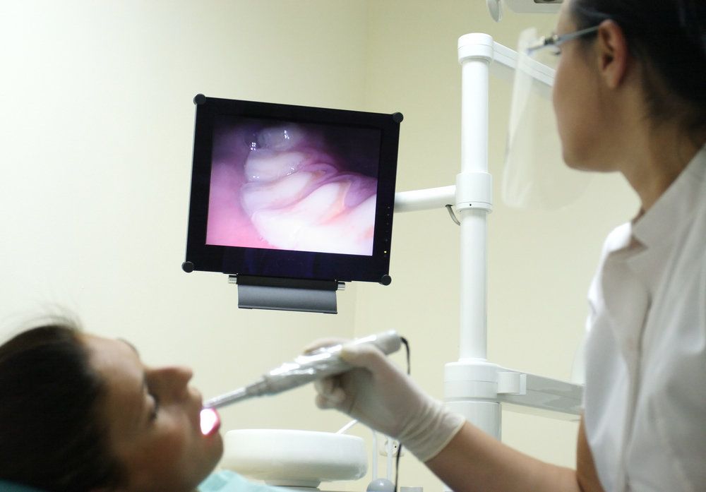 <p>A dentist holding an intraoral camera within a patient's mouth.</p>